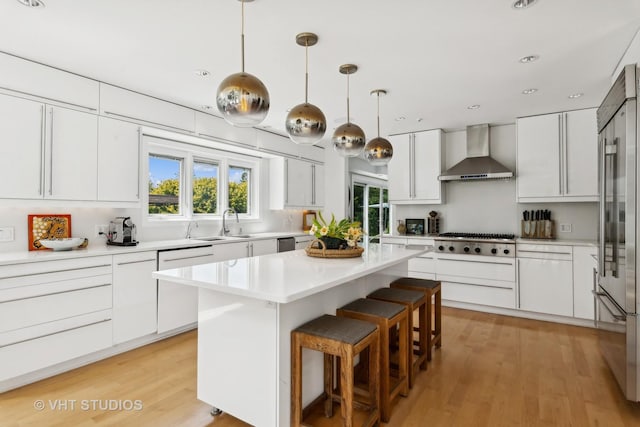 kitchen with wall chimney range hood, stainless steel appliances, white cabinetry, and a healthy amount of sunlight