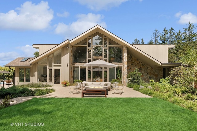 back of house featuring french doors, a lawn, an outdoor hangout area, a patio, and stone siding