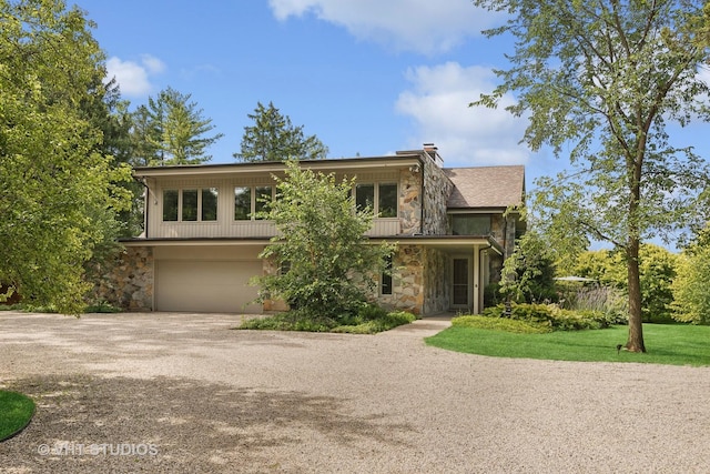 view of front of house featuring a garage, a chimney, stone siding, and dirt driveway