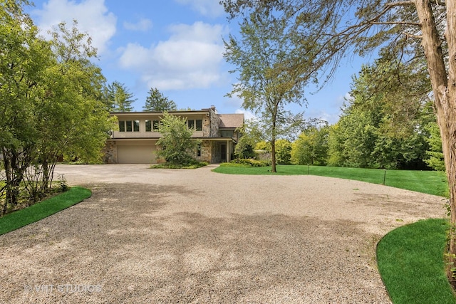 view of front of property with an attached garage, a front yard, driveway, and stone siding