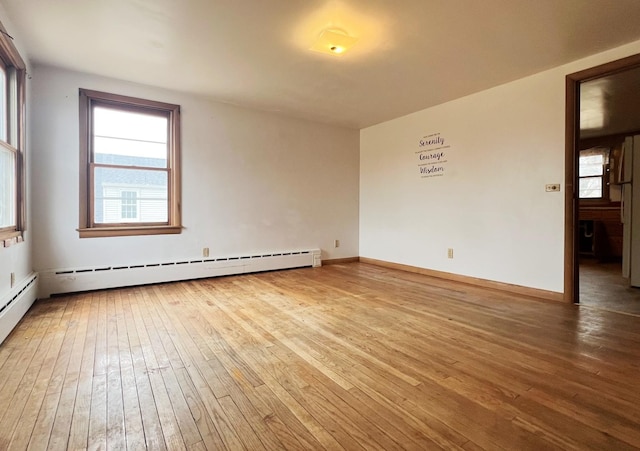 empty room featuring hardwood / wood-style floors, baseboards, and baseboard heating