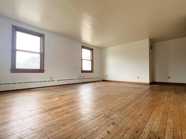 empty room with baseboards, light wood-type flooring, and a baseboard radiator