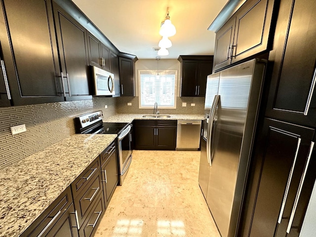 kitchen with a sink, light stone counters, tasteful backsplash, stainless steel appliances, and hanging light fixtures