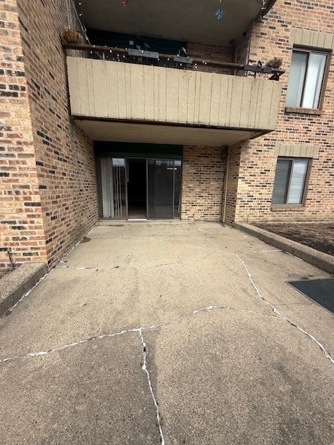 property entrance featuring a patio and brick siding