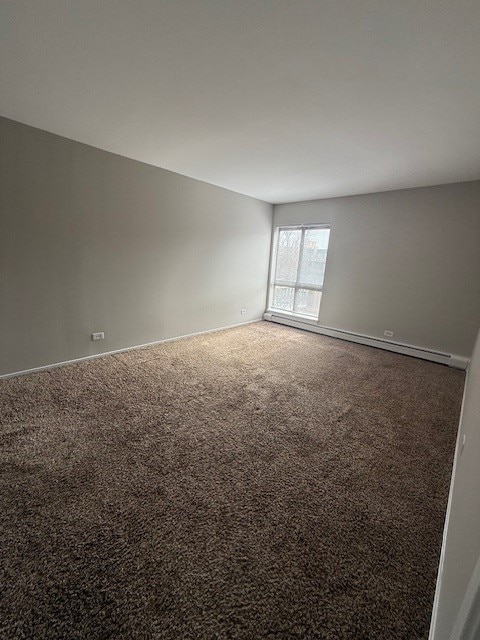 empty room with a baseboard heating unit and carpet floors