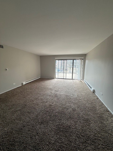 empty room featuring carpet flooring, visible vents, and a baseboard radiator