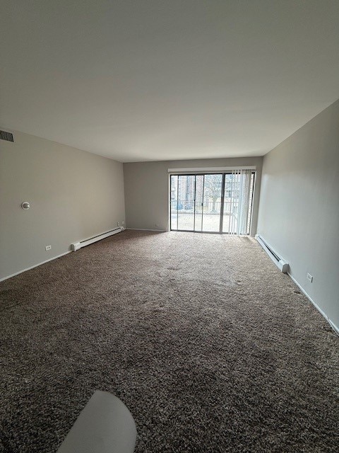 carpeted spare room featuring a baseboard radiator and visible vents