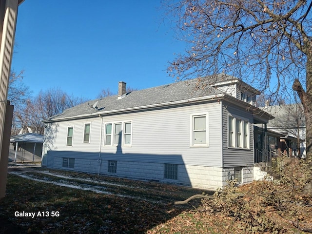 rear view of house featuring a chimney and a shingled roof