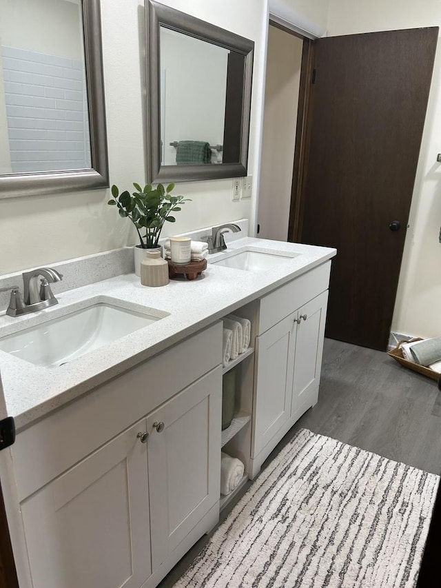 full bathroom with double vanity, wood finished floors, and a sink