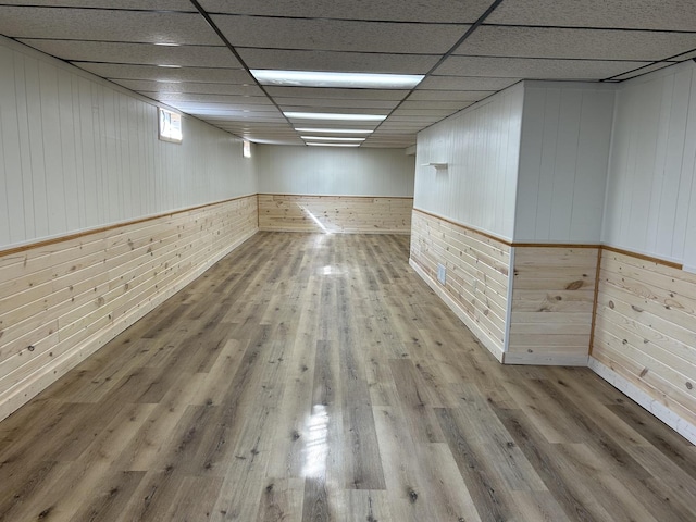 unfurnished room with wood walls, a paneled ceiling, and wood finished floors