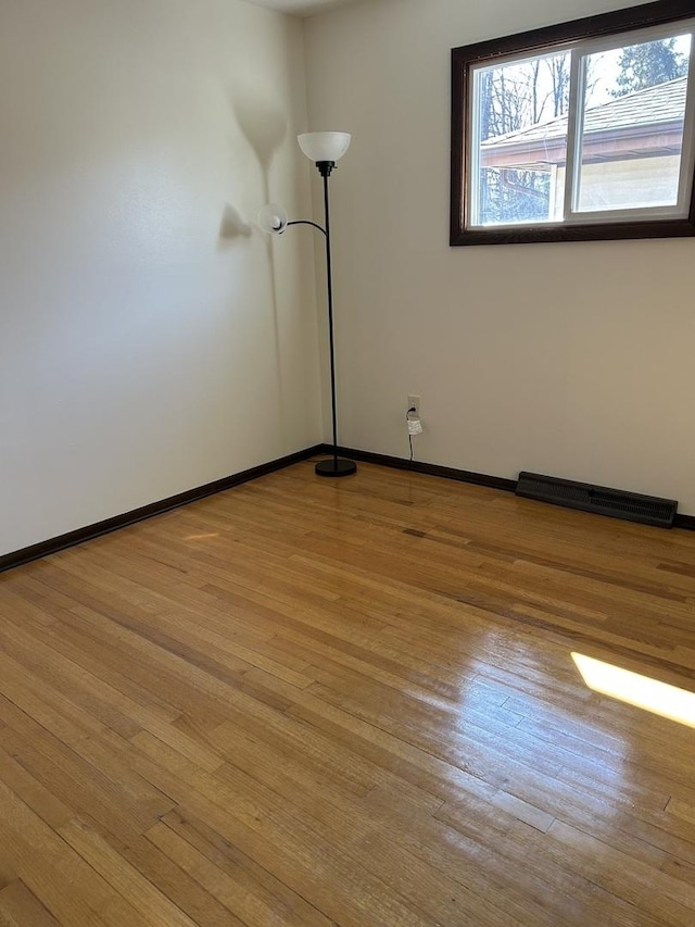 empty room featuring visible vents, baseboards, and wood finished floors