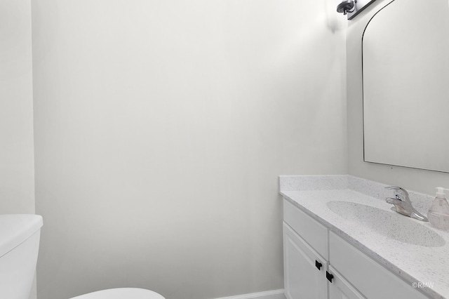 half bath with baseboards, toilet, and vanity