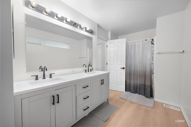 bathroom featuring double vanity, visible vents, wood finished floors, and a sink