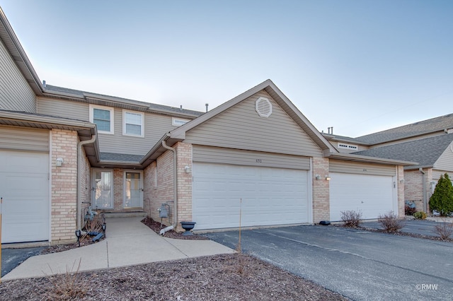 view of front facade with aphalt driveway, brick siding, and a garage