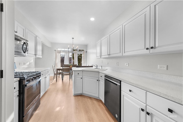 kitchen with a sink, appliances with stainless steel finishes, white cabinets, and an inviting chandelier