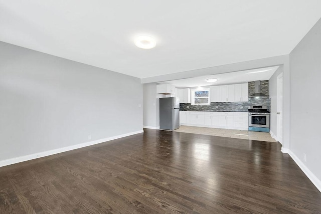 unfurnished living room with light wood-type flooring and baseboards