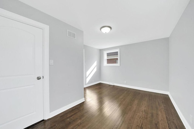 unfurnished room with visible vents, baseboards, and hardwood / wood-style flooring