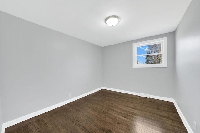 unfurnished room with baseboards and dark wood-style floors