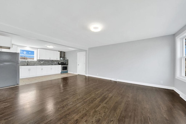 unfurnished living room with light wood-style flooring, baseboards, and a sink