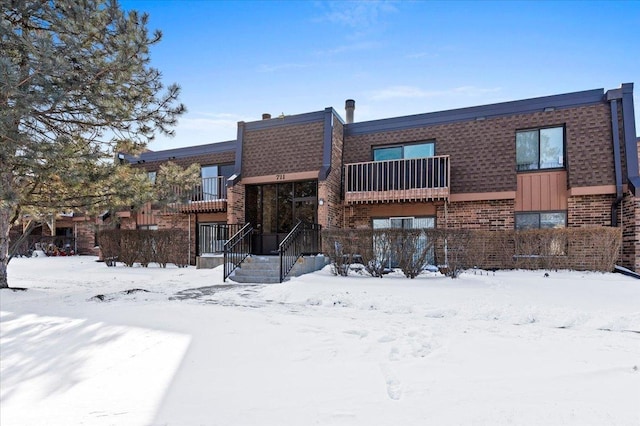 view of front of property with brick siding and a balcony