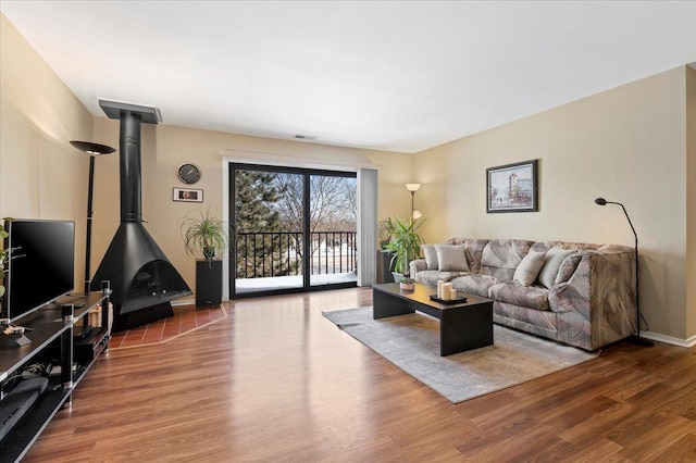 living area with visible vents, a wood stove, baseboards, and wood finished floors