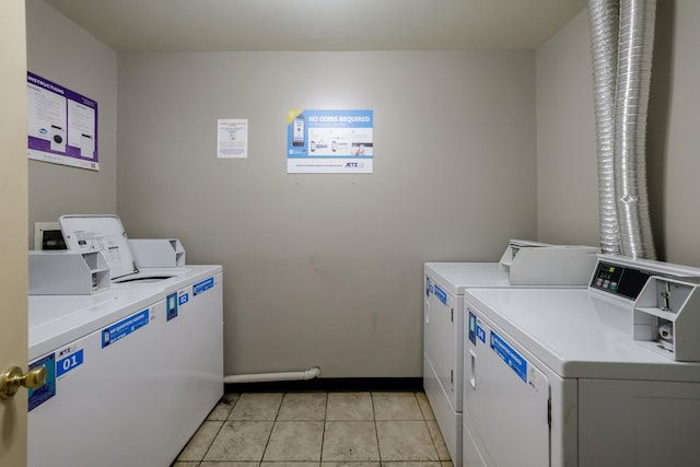 community laundry room with light tile patterned floors, washer and dryer, and baseboards