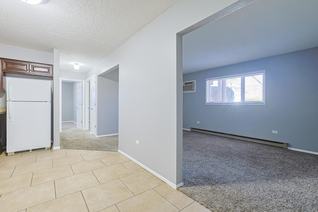 empty room featuring a wall unit AC, light tile patterned floors, a textured ceiling, a baseboard heating unit, and light carpet