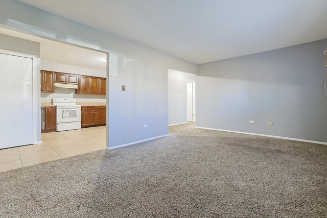 unfurnished living room featuring light tile patterned floors, light colored carpet, and baseboards