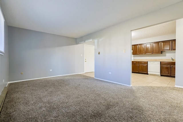 unfurnished living room featuring light tile patterned flooring, light colored carpet, baseboards, and a sink