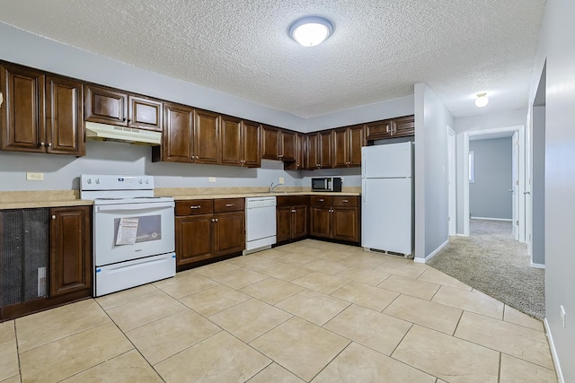 kitchen featuring white appliances, a sink, light countertops, dark brown cabinetry, and under cabinet range hood