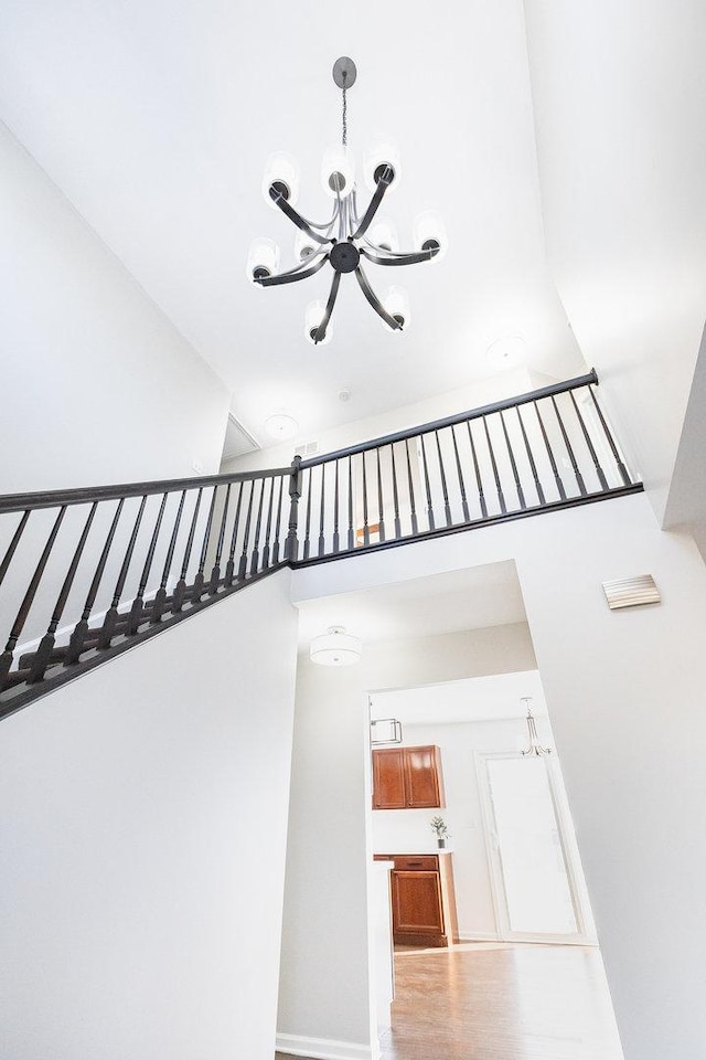 stairs featuring a notable chandelier, a high ceiling, and wood finished floors