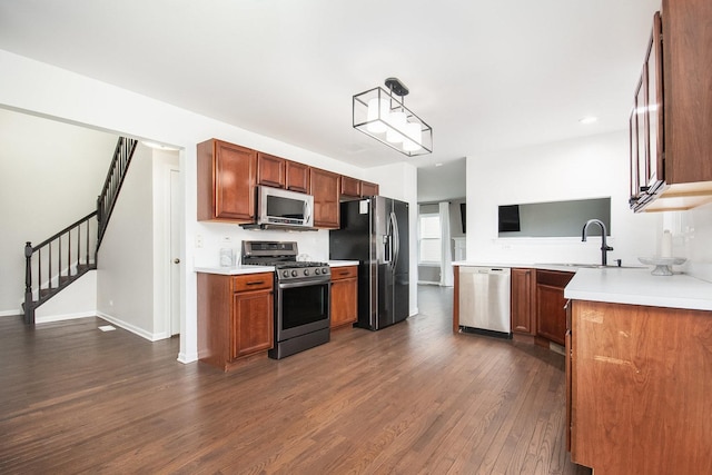 kitchen featuring baseboards, a sink, dark wood-type flooring, light countertops, and appliances with stainless steel finishes