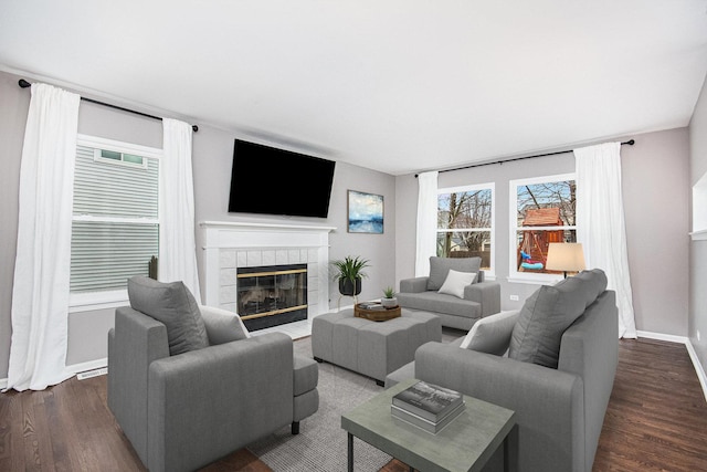 living room featuring baseboards, dark wood-style floors, and a tiled fireplace