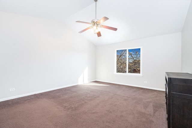 spare room featuring dark carpet, baseboards, ceiling fan, and vaulted ceiling