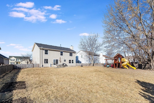 rear view of house featuring a lawn, a fenced backyard, a playground, a chimney, and a patio area