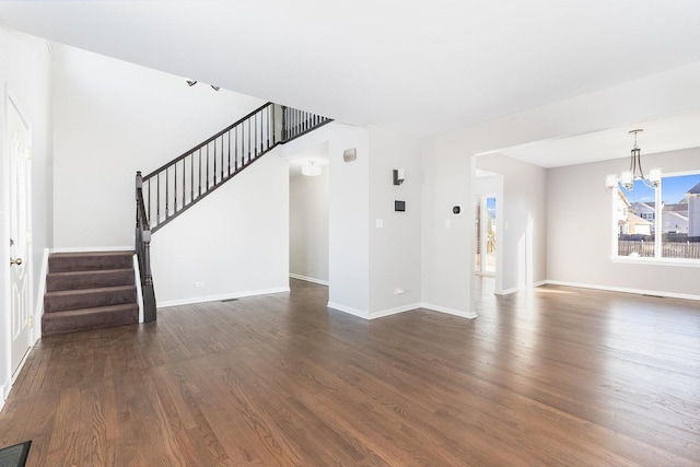 unfurnished living room featuring stairway, baseboards, visible vents, dark wood-type flooring, and a chandelier