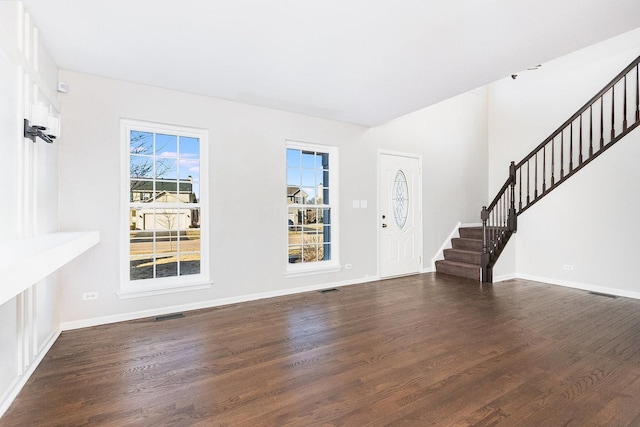 foyer entrance featuring dark wood finished floors, stairway, baseboards, and visible vents