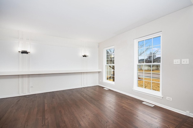 unfurnished room with visible vents, baseboards, and dark wood-style floors