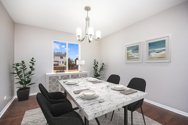 dining space featuring dark wood-style floors, a notable chandelier, and baseboards