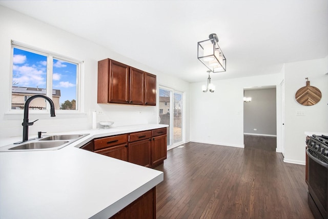 kitchen with dark wood-type flooring, black gas range oven, light countertops, and a sink