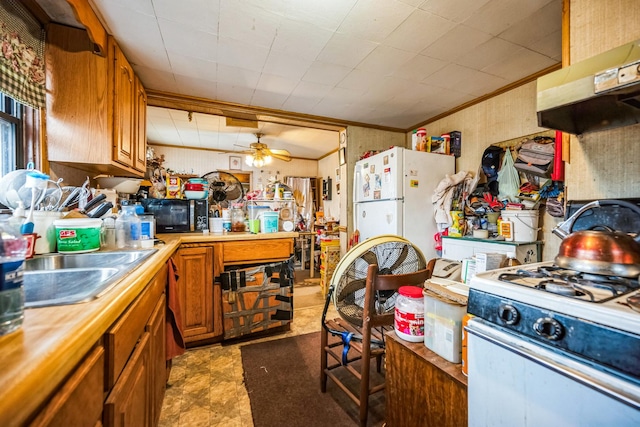 kitchen featuring crown molding, under cabinet range hood, light countertops, white appliances, and a sink