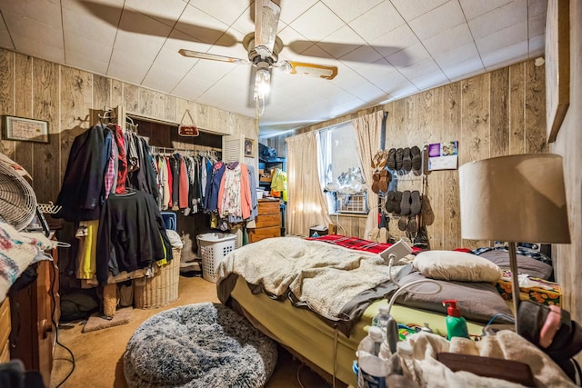 bedroom with wood walls, carpet floors, and ceiling fan