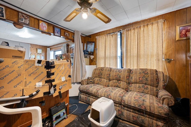 living area featuring a ceiling fan and wood walls