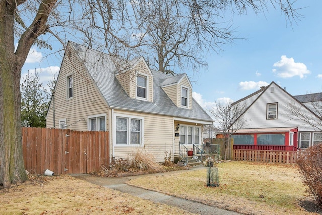 cape cod house with a front lawn and fence