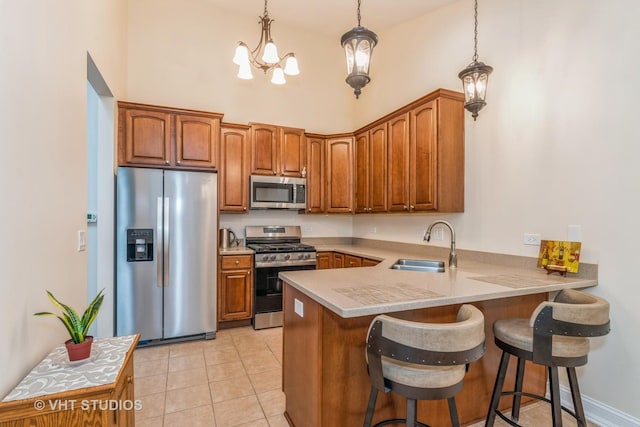 kitchen featuring light tile patterned floors, a peninsula, a sink, appliances with stainless steel finishes, and a kitchen bar