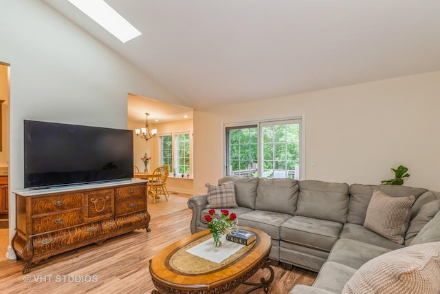 living room with a skylight, light wood-style floors, a chandelier, and high vaulted ceiling