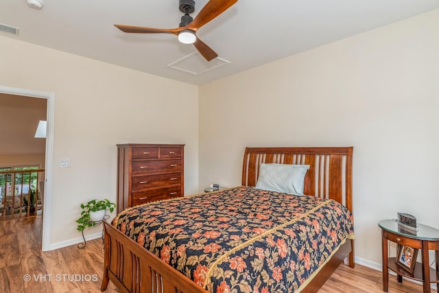 bedroom with light wood-type flooring, visible vents, baseboards, attic access, and ceiling fan