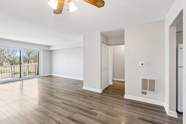 unfurnished room with visible vents, baseboards, a ceiling fan, and dark wood-style flooring