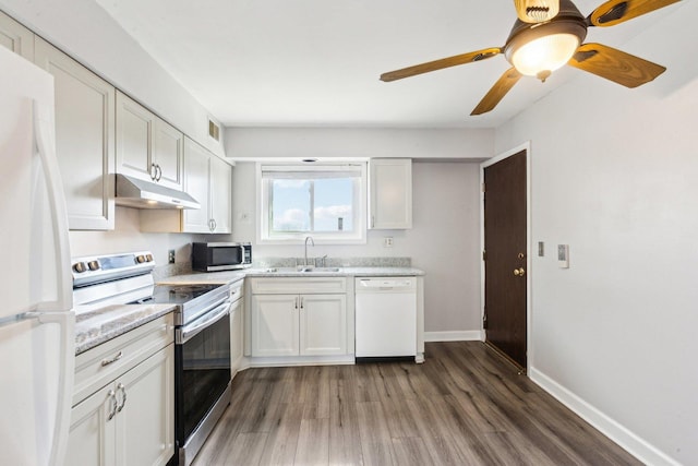 kitchen featuring under cabinet range hood, appliances with stainless steel finishes, wood finished floors, white cabinetry, and a sink