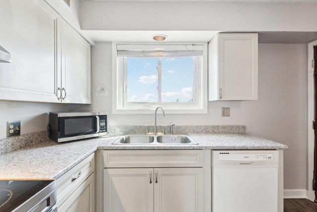 kitchen with stainless steel microwave, light countertops, white dishwasher, white cabinetry, and a sink